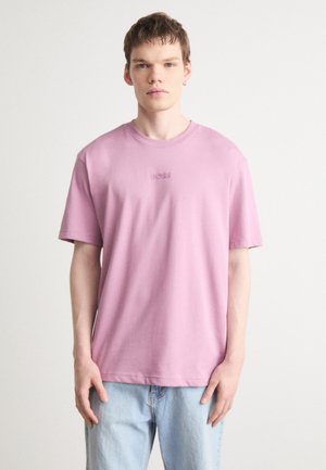 T-shirt en coton rose clair à manches courtes avec un col rond côtelé et un logo "BOSS" brodé sur la poitrine. Porté avec un jean bleu clair.