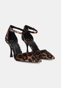 Zapatos de tacón alto con print de leopardo, tirante en el tobillo, punta afilada y tacón de aguja negro. Material de gamuza suave con un acabado brillante.