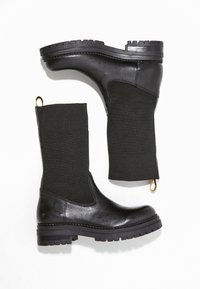 Svarta ankelstövlar med en slät läderbotten, ribbat stickat ovansidan, guldögla-detalj och texturerad gummisula för grepp och hållbarhet.