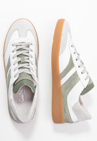 Pair of white and green suede sneakers with brown rubber soles, laces, and textured side panels on a white background.