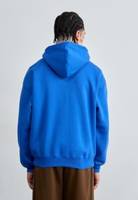 Blauwe pullover hoodie met een grote capuchon, gemaakt van een zachte katoenen stofmix. Voorzien van ribgebreide manchetten en zoom, met een soepele textuur en een relaxte pasvorm.