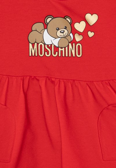 Rdeča bombažna obleka z grafiko medvedka in srčki, zlatim napisom "Moschino" in nabranim krilom ter stranskimi žepi.
