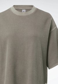 Tyrkysové ribbené tričko s kulatým výstřihem a krátkými rukávy. Vyrobeno z texturované tkaniny s malou etiketou na lemu.