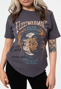 Gray cotton t-shirt featuring a graphic print with “Fleetwood Mac” and “Sister of the Moon” text in orange and teal, rounded hem.