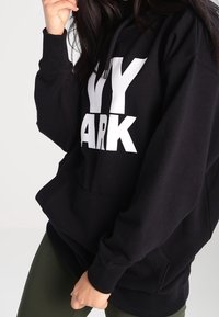 Sudadera negra de mezcla de algodón, con un gran texto gráfico en blanco "NY PARK" en la parte frontal y un bolsillo delantero.