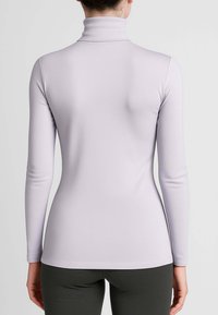 Maglia a maniche lunghe color lavanda chiaro con collo alto, realizzata in tessuto elasticizzato e liscio, con una silhouette aderente e un colletto stretto.