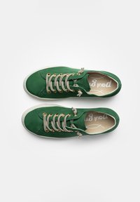 Grüne Canvas-Sneaker mit beigen Schnürsenkeln und goldenen Ösen. Sie verfügen über eine weiße Gummisohle und ein strukturiertes Obermaterial für zusätzlichen Grip.
