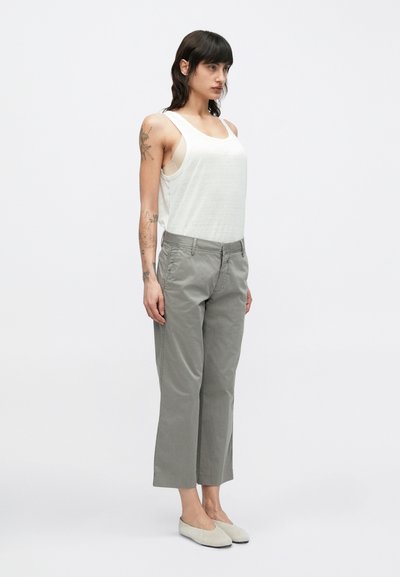 Pantalon court gris clair en coton, avec une coupe droite, des poches avant, et un design à l'avant plat. Associé à un débardeur blanc.