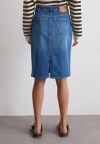 Denim rok in medium blauw met een rechte snit, zichtbare stiksels, een split achteraan en twee achterzakken. Leren label op de tailleband.