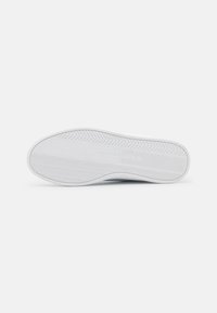 Sole di sneaker bianca con un motivo a spina di pesce testurizzato, dotata di una superficie liscia e un sottile dettaglio di branding. Design pulito e minimal.