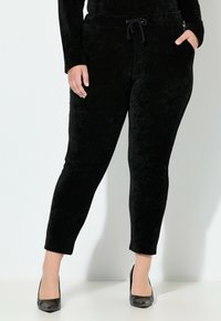 Zwarte corduroy joggerbroek met een aansluitende pasvorm, zijzakken en een trekkoord in de tailleband, met een zachte textuur en een strak design.