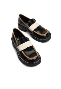 Czarne skórzane mokasyny na grubej podeszwie, z brązową obwódką wokół przodu i szerokimi białymi paskami na górze, na białym tle.