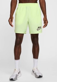 Pantalones cortos deportivos de color amarillo neón con cinturilla elástica, que presentan un gráfico negro de "RUN" y el logo del swoosh de Nike. Tejido texturizado, diseño hasta la rodilla.