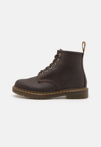 Bottines en cuir marron avec un bout rond, quincaillerie dorée, design à lacets et couture jaune contrastante le long de la semelle.