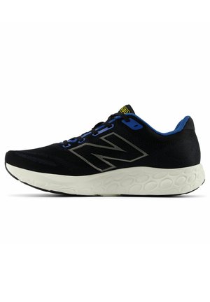 Zapatilla deportiva negra con parte superior texturizada, acentos azules y gran logotipo plateado. Presenta una suela blanca gruesa y acolchada con un diseño estampado.