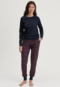 Marineblauwe sweater met geribbelde manchetten, gecombineerd met gestreepte joggingsbroeken in donkerblauw met roze harten, voorzien van een elastische tailleband en zakken.