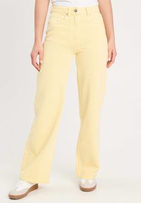 Jean large taille haute de couleur jaune en denim, avec fermeture à bouton, passants de ceinture et design à cinq poches.