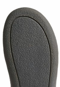 Černá gumová podrážka obuvi s texturovaným, protiskluzovým povrchem a hladkým okrajem; oválný tvar s vymezenou hranou pro strukturální podporu.