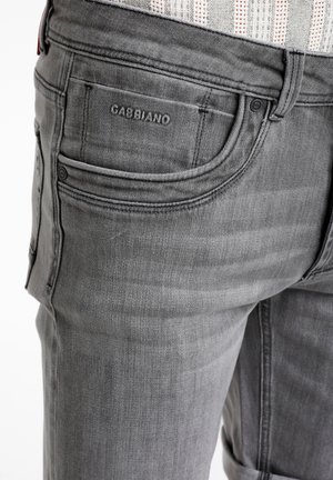 Sive podatkovne kavbojke z zakladnim dizajnom petih žepov. Tkanina ima rahlo teksturo, z izrazitim logotipom blagovne znamke na zadnjem žepu.