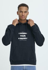 Navy hoodie with a front pocket, featuring a white graphic design that reads "EXPAND YOUR MINDSET" in bold text. Cotton material, relaxed fit.
