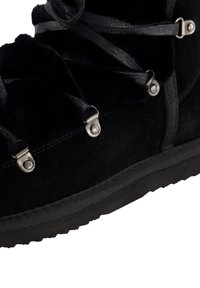 Czarne zamszowe buty z syntetycznym futerkiem w środku, płaskimi sznurówkami, metalowymi oczkami oraz gumową podeszwą z teksturowanymi wzorami.