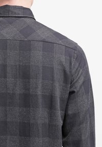Camicia in flanella grigio scuro con motivo a quadri, dotata di colletto classico e parte posteriore con yoke, realizzata in tessuto morbido e strutturato.