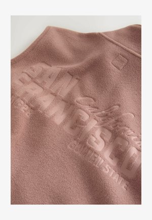 Fleece vest in soft pink with embossed "SAN FRANCISCO" text. Features a rounded collar and subtle texture. Clean, minimalist design with logo detail.