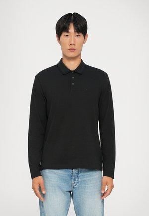 Zwarte polo met lange mouwen, gemaakt van zachte stof, met een geribbeld kraag, drukknopen met drie knopen en een subtiel logo op de borst.