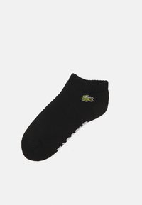 Chaussette noire de cheville en mélange de coton, avec un logo de crocodile vert et des lettres blanches sur le côté. Bord ribbed en haut.