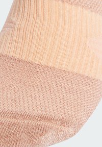 Calcetín rosa claro con diseño de punto texturizado, que presenta secciones suaves y acanaladas, una puntera sin costuras y un puño suave y elástico.
