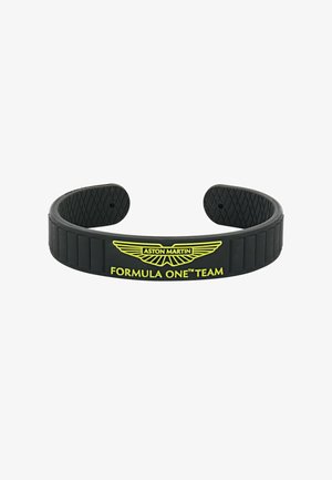 Fekete gumiszíj, amelyen dombornyomott Aston Martin logó és élénksárga "FORMULA ONE™TEAM" felirat látható. Belső oldalán mintázott felület.