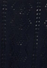 Tissu tricoté bleu foncé avec des motifs en dentelle florale et géométrique complexes, créant des détails texturés semi-transparents.