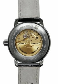 Automatic wristwatch with a stainless steel case, transparent back, gold-toned movement, and black leather strap. Detailed engravings present.