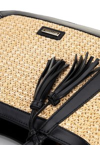 Sac en cuir noir et en paille tissée avec une surface texturée, des poignées en cuir noir et des franges décoratives. Accent de logo doré sur la surface.