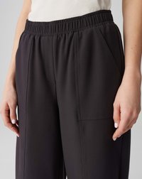 Black, lightweight pants with an elastic waistband, side pockets, and smooth texture. Features tailored seams and a relaxed fit design.