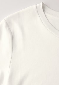 Lys hvid kortærmet T-shirt med rund hals, vist fladt for at fremhæve stofteksturen og syningerne.