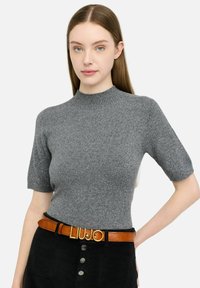 Maglione grigio a maniche corte con scollatura a costine, maglia lavorata a trama e leggero effetto scintillante. Abbinato a una cintura in pelle marrone con fibbia dorata.