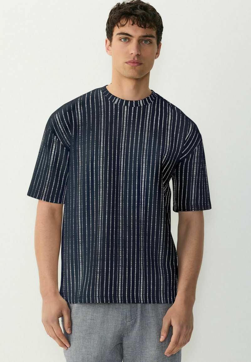 Tricou scurt cu mânecă pentru bărbați, de culoare bleumarin, cu un model vertical de dungi albe, decolteu rotund și croială lejeră. Material moale cu o ușoară textură.