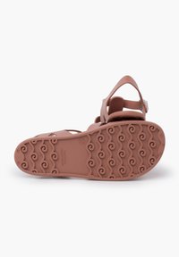 Brown rubber sandal with a textured wavy sole, adjustable strap, and cut-out design at the front. Features brand logo on the sole.