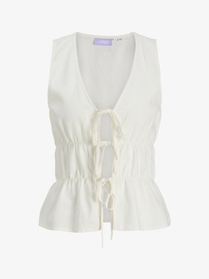 Blouse blanche sans manches avec col en V profond, taille froncée, bas volanté et trois liens devant pour la fermeture.