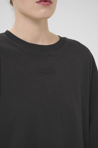 Zwarte katoenen t-shirt met een ronde hals en korte mouwen. Beschikt over een textuur logo patch in het midden van de borst. Glad stofgevoel.