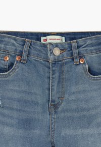 Lyhyet leveälahkeiset farkut vaaleansinisinä. Varustettu kupariseoksesta valmistetuilla niiteillä, kontrastivärillisellä ompeleella ja vyötäröllä "Levi's"-logolla varustetulla tarralla.