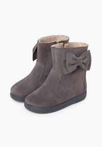 Bottes chelsea en suède gris avec un grand nœud sur le côté, une doublure douce et une semelle en caoutchouc pour une meilleure adhérence. Fermeture à glissière pour un enfilage facile.