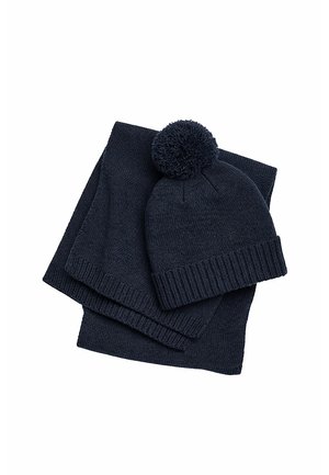 Dark blue knitted winter hat with pom-pom and matching scarf, both folded and placed on a white background.