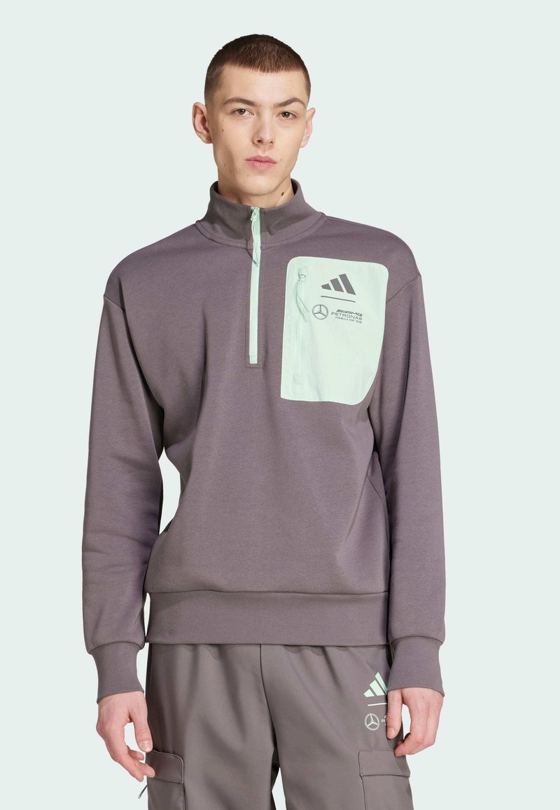 Felpa grigia con zip e tasca verde menta, con il logo e il testo Adidas. Texture liscia, design casual e polsini a costine.