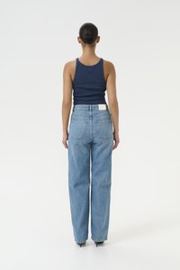 Μπλε ριγέ αμάνικο μπλουζάκι συνδυασμένο με ψηλόμεσο ανοιχτό μπλε παντελόνι με φαρδύ πόδι. Περιλαμβάνει ετικέτα μ patch στη πίσω μέση και τέσσερις τσέπες.