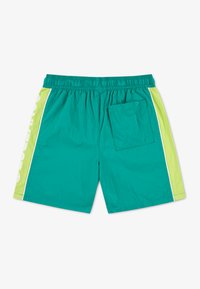 Τιρκουάζ μαγιό σορτς με ελαστική μέση, αντίθετα πλευρικά πάνελ σε φωτεινό πράσινο και μία πίσω τσέπη. Ελαφρύ, με λεία υφή.