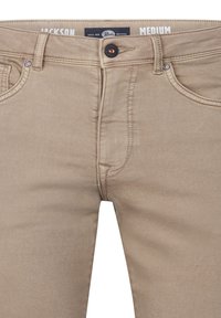 Pantalon en coton beige au design ajusté, avec fermeture par bouton, poches cousues et texture lisse. Étiquette indique "moyen."
