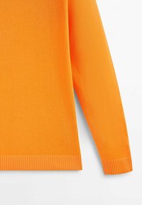 Pomarańczowy dziergany sweter o miękkiej, teksturowanej powierzchni. Ma ściągacz na dole i przy mankietach. Projekt obejmuje długie rękawy i zaokrąglony dekolt.