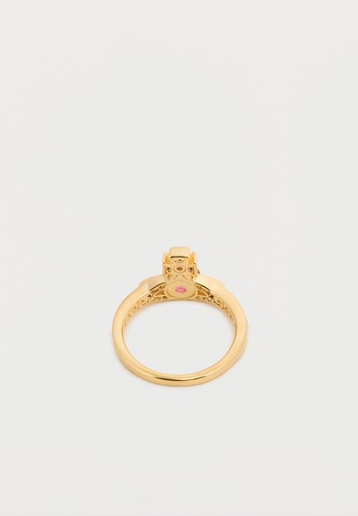 Χρυσό δαχτυλίδι με εγχάρακτη ταινία και τετράγωνη βάση που κρατά μια μικρή ροζ πολύτιμη πέτρα, εμφανιζόμενο σε λευκό φόντο.